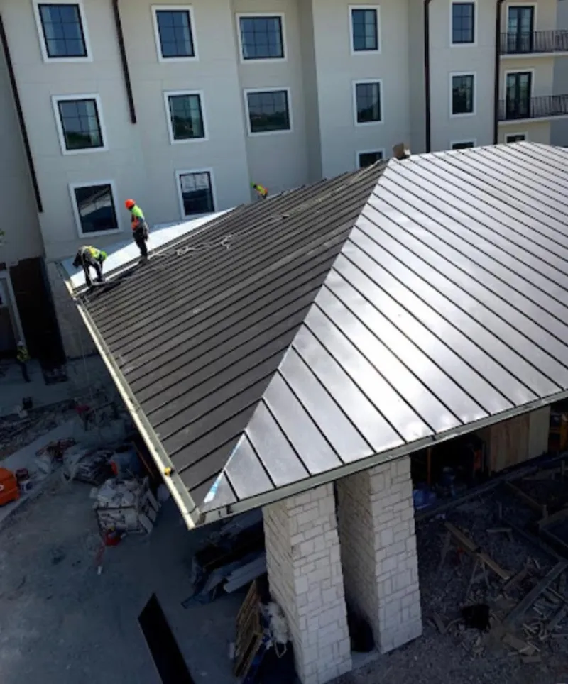 Crew installing standing seam metal roof panels on a commercial project in Dunn
